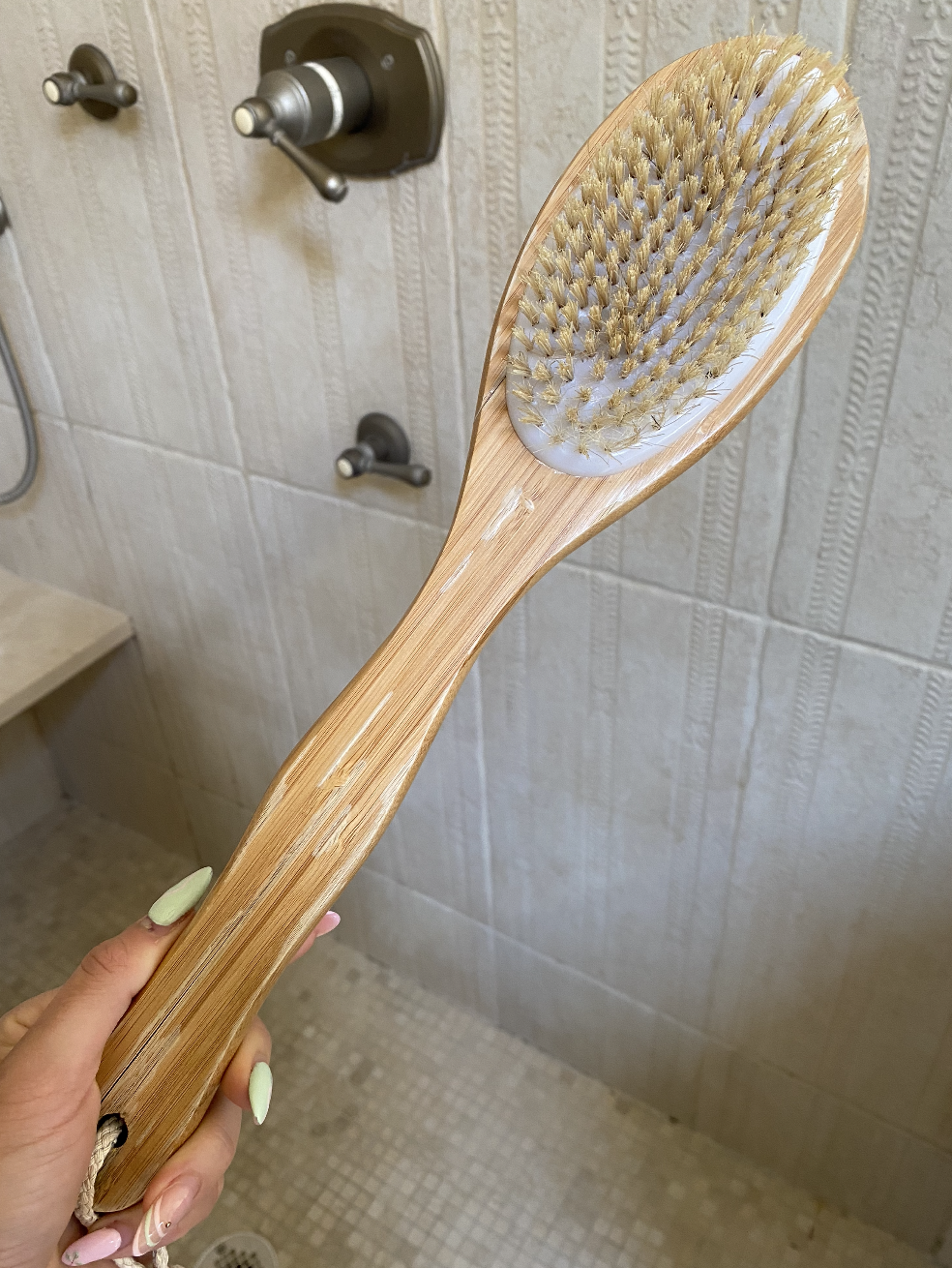 The author holding up a bristle brush in her shower