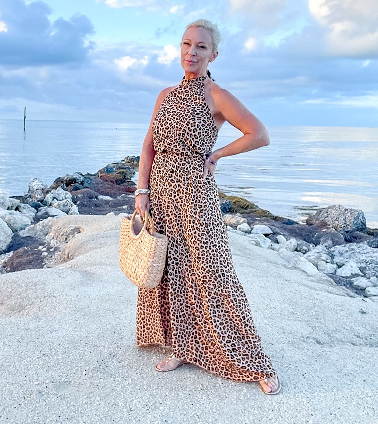 a reviewer wearing the dress in leopard print by the ocean