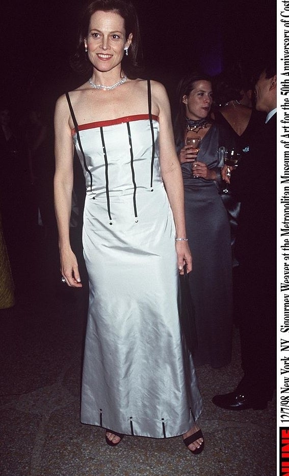 Sigourney wears a long thin-strapped dress with 4 lines going down mid-way