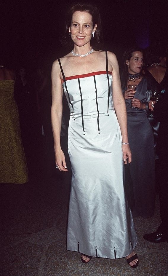 Sigourney wears a long thin-strapped dress with 4 lines going down mid-way