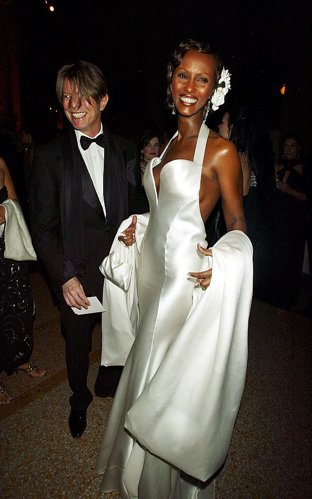 Iman wearing a long silver shiny gown with a halter top