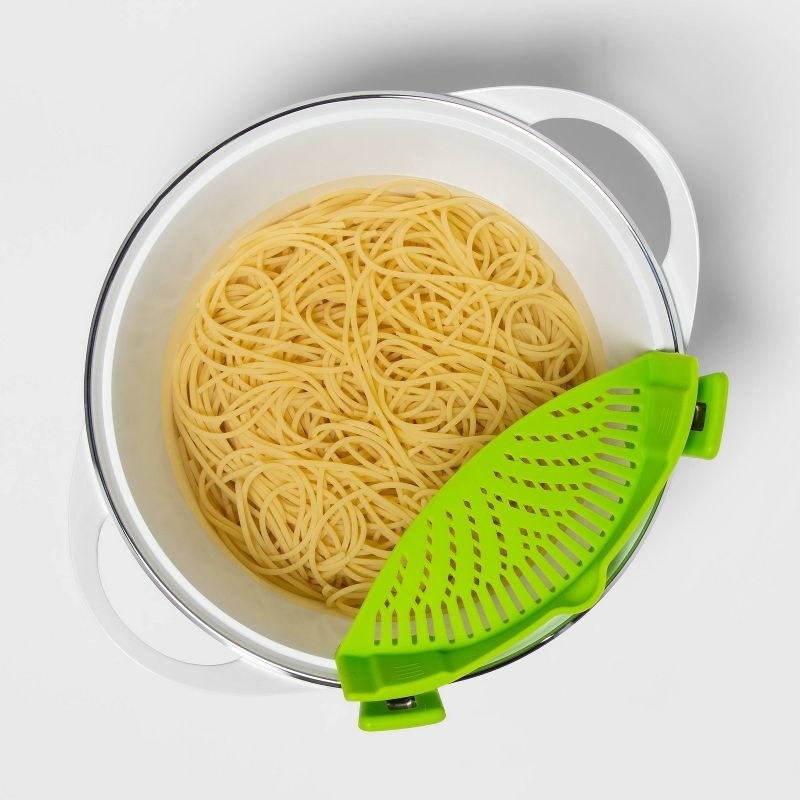 lime green colored clip on strainer on a pot with pasta inside