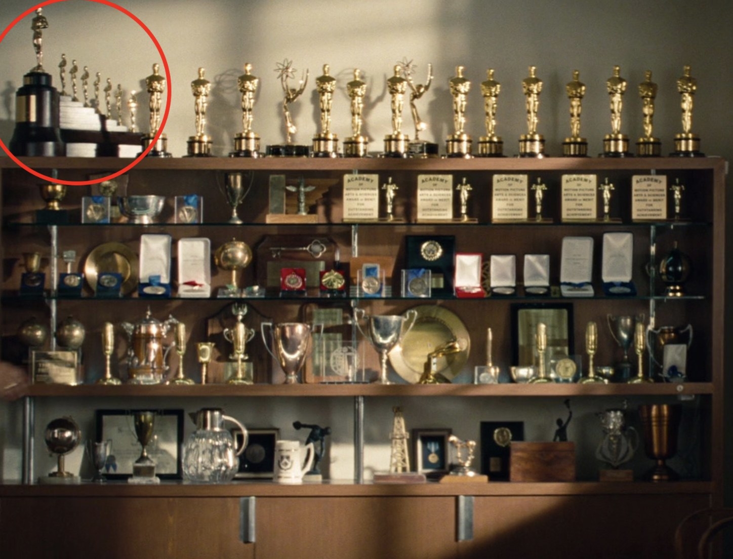 The smaller Oscars are on a shelf of awards