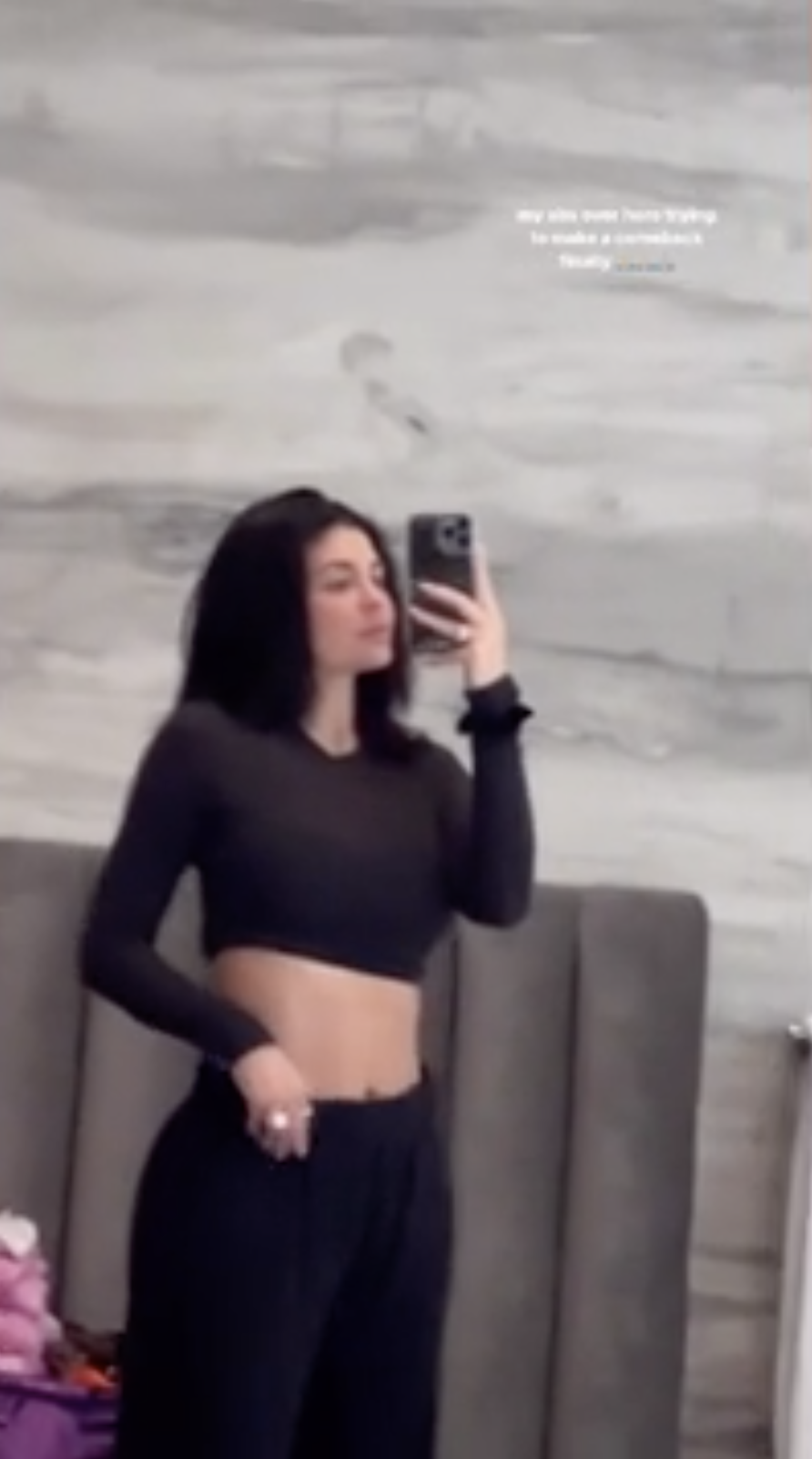 a grainy selfie of Kylie in a crop top and jogger sweatpants