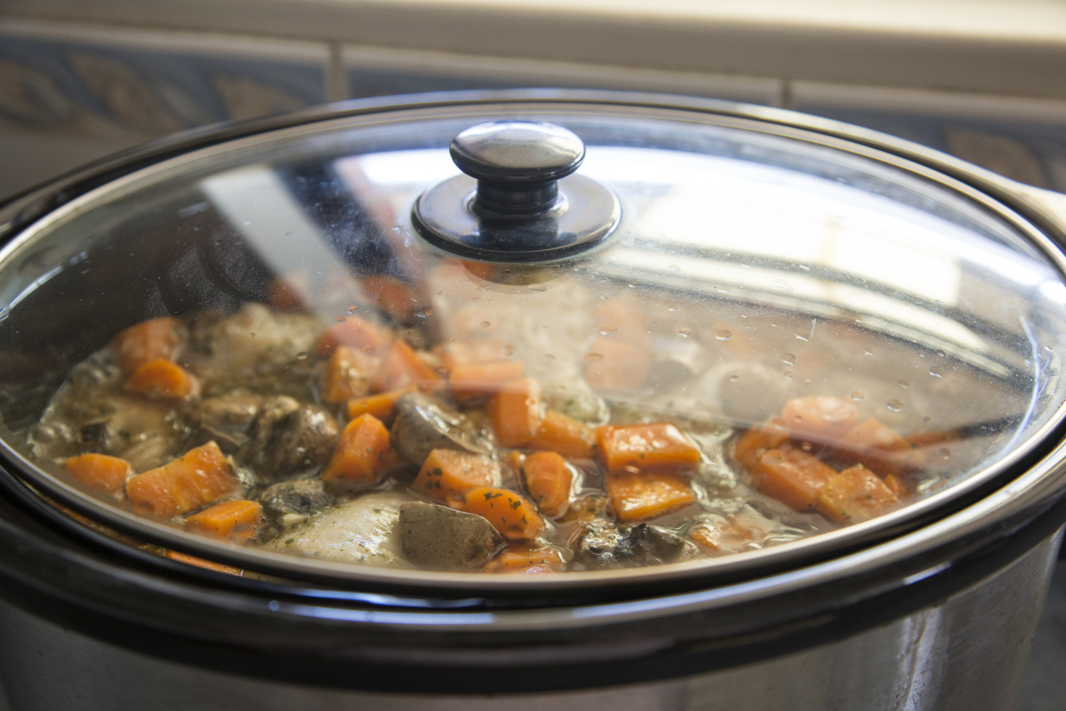 A beef dish with carrots in a slow cooker.