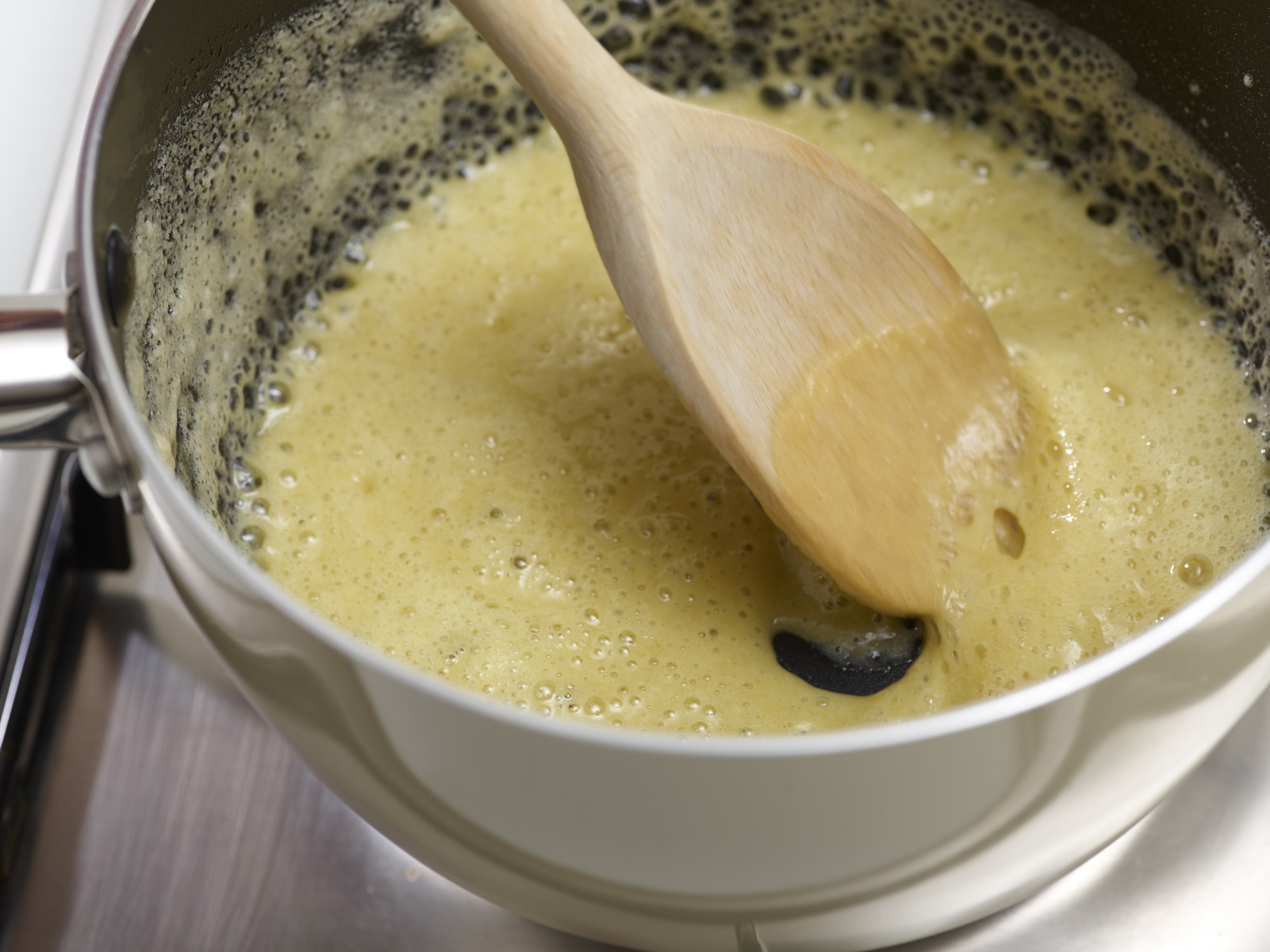 Melting butter in a pan and stirring in flour to make a roux.
