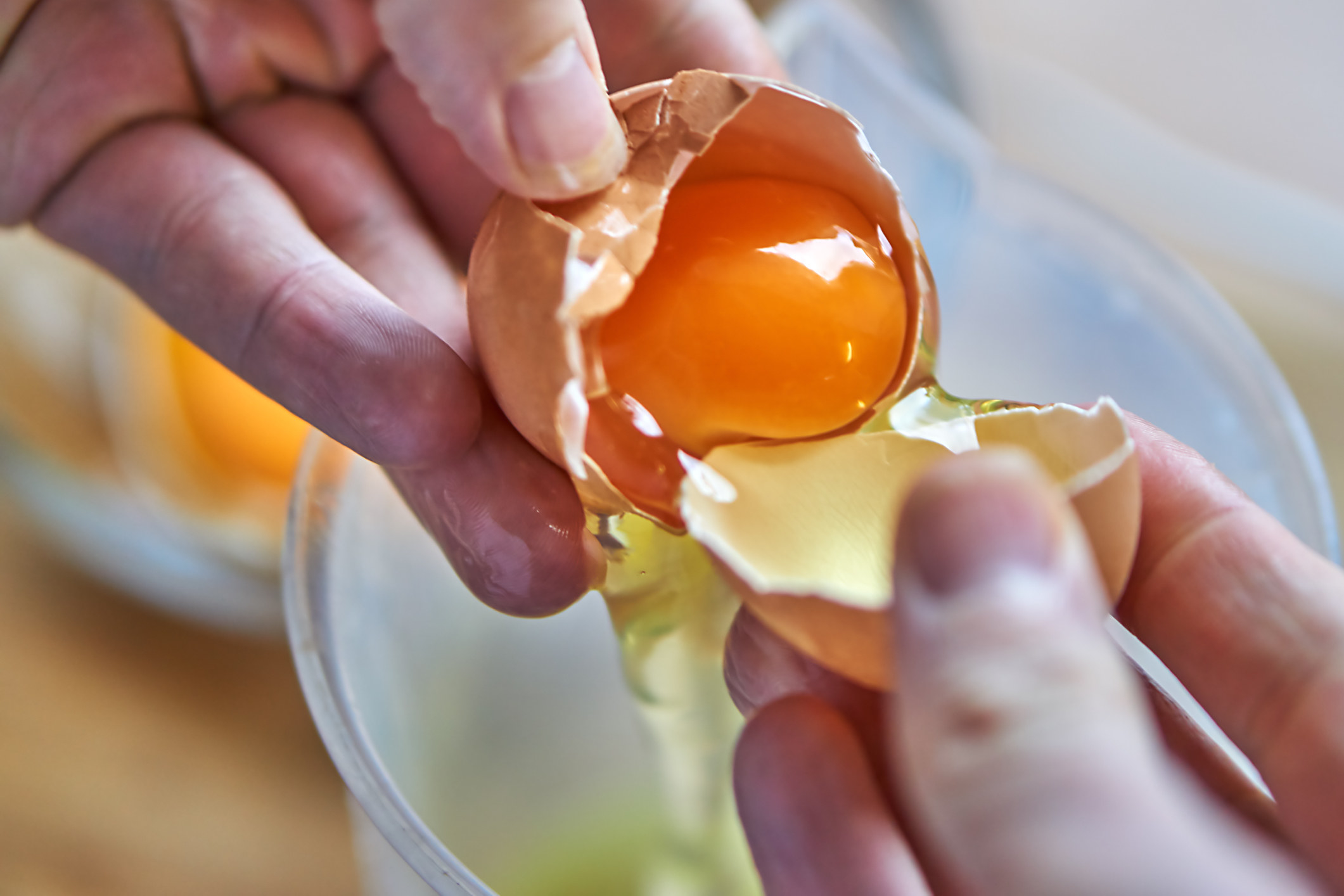 Hands separating an egg yolk from the whites.