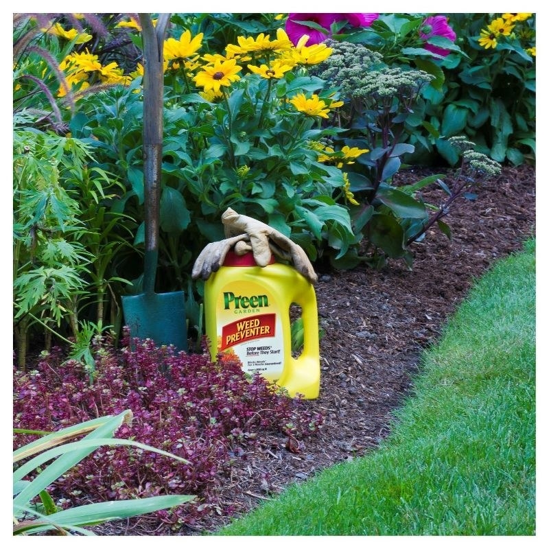 The weed killer in a mulch garden with gloves resting on top and shovel next to it