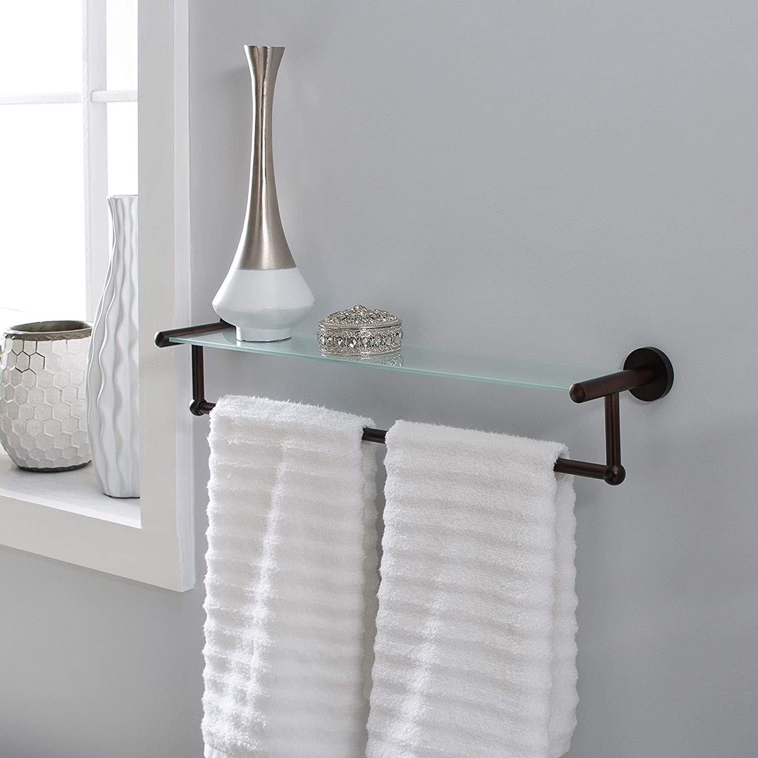 The shelf with two white towels, a vase, and a trinket displayed on it