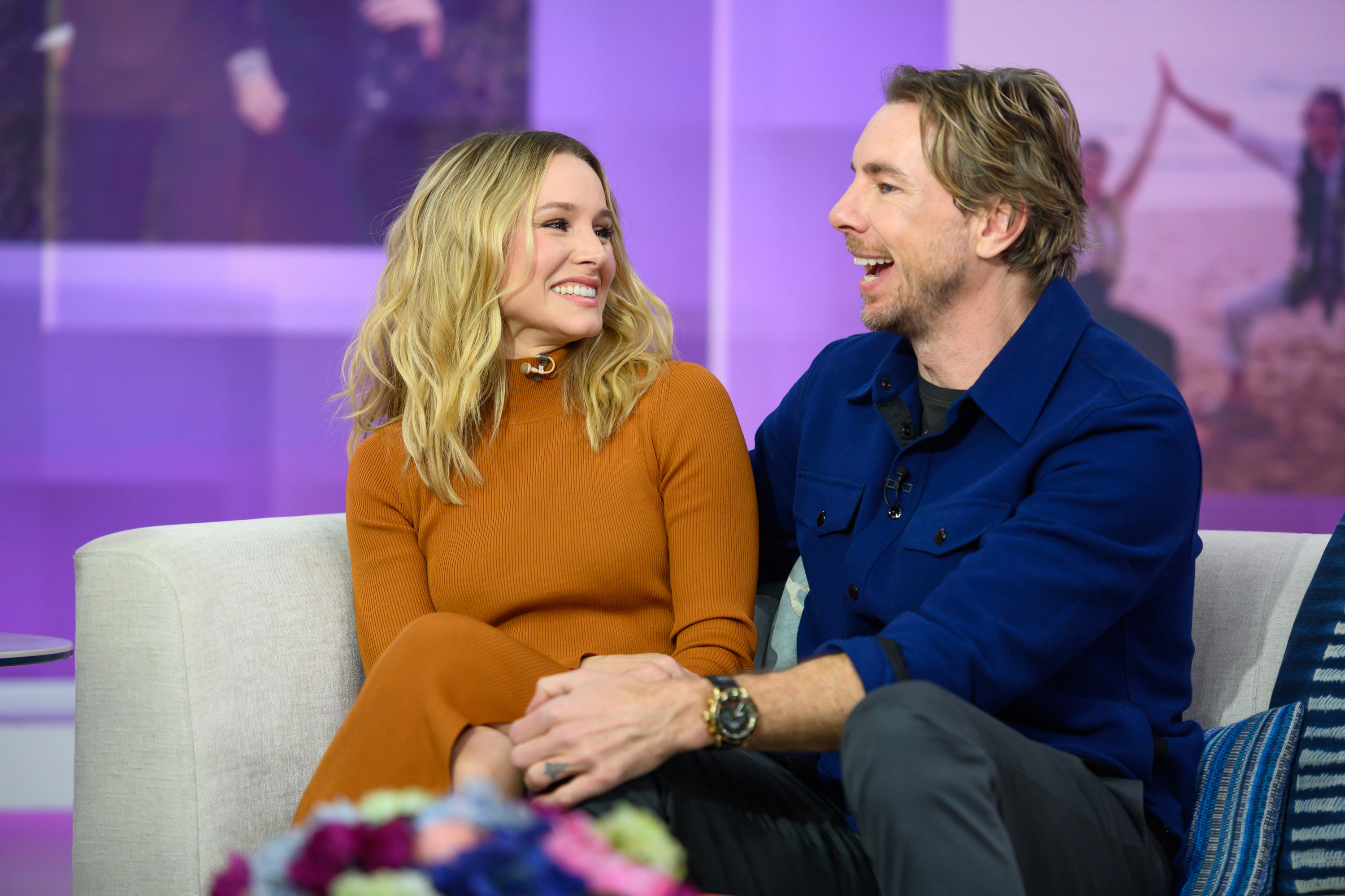 Kristen Bell and Dax Shepard sitting on a couch and laughing
