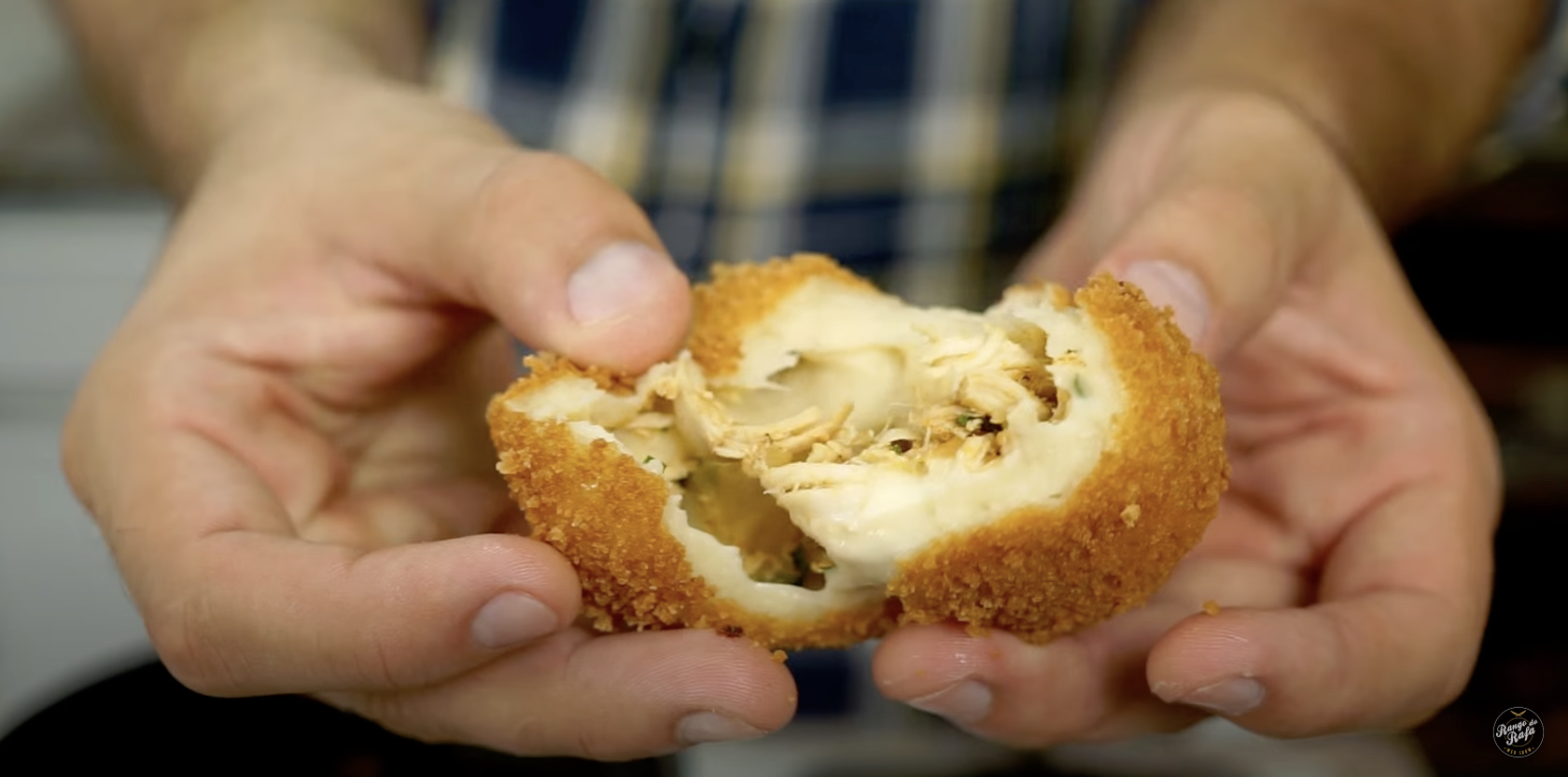A person holding a coxinha pulled apart
