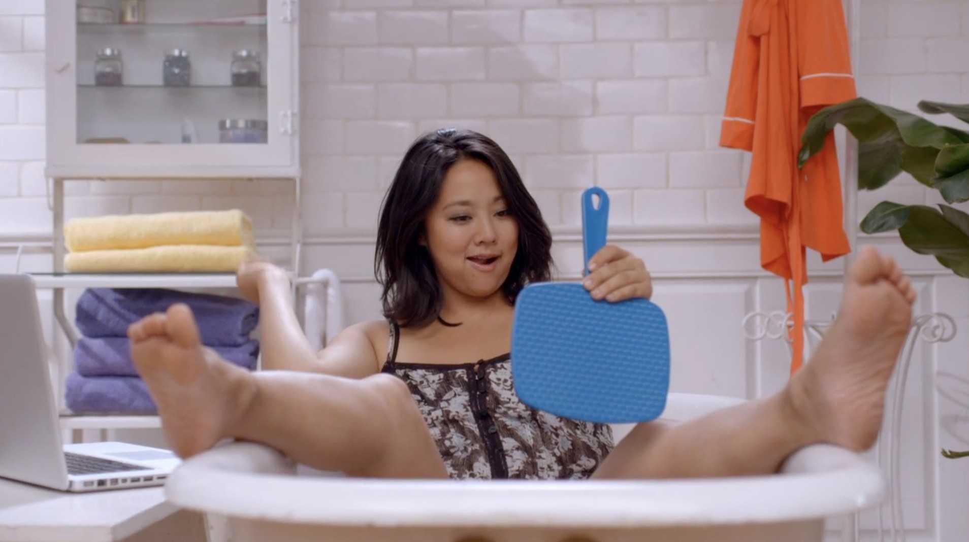 Stephanie Hsu in the bathtub with a handheld mirror in Girl Code. 