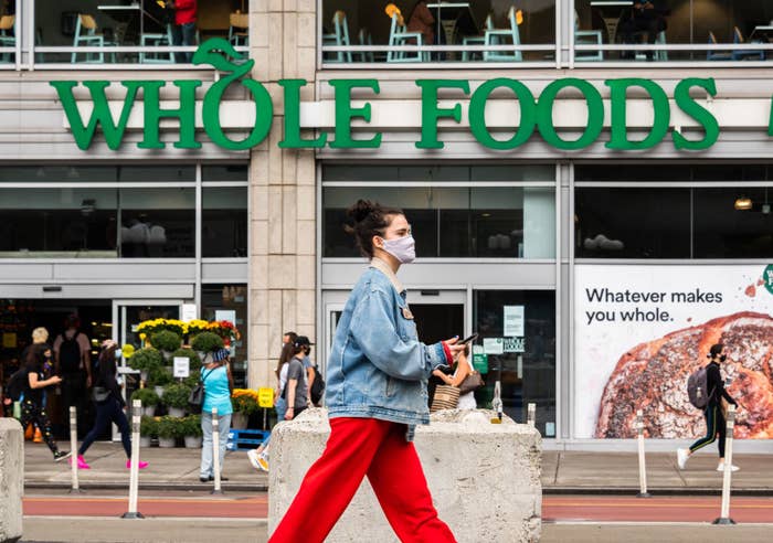 A woman walking in front of Whole Foods.