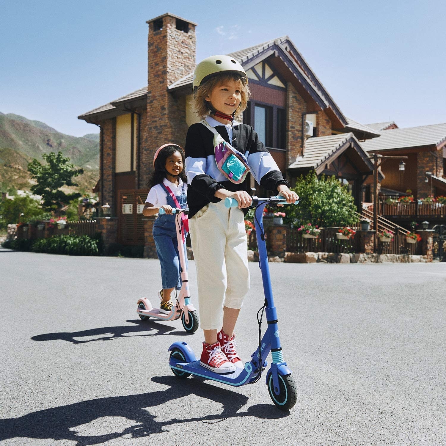kids riding a blue and pink scooter