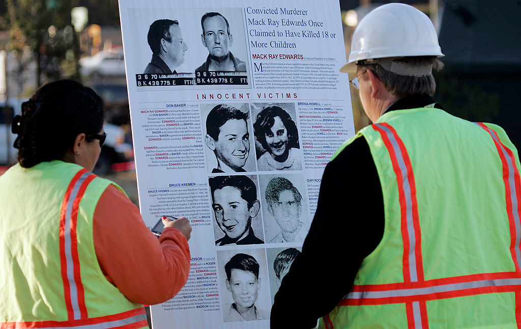 two people in construction gear looking at a large poster of all the child victims