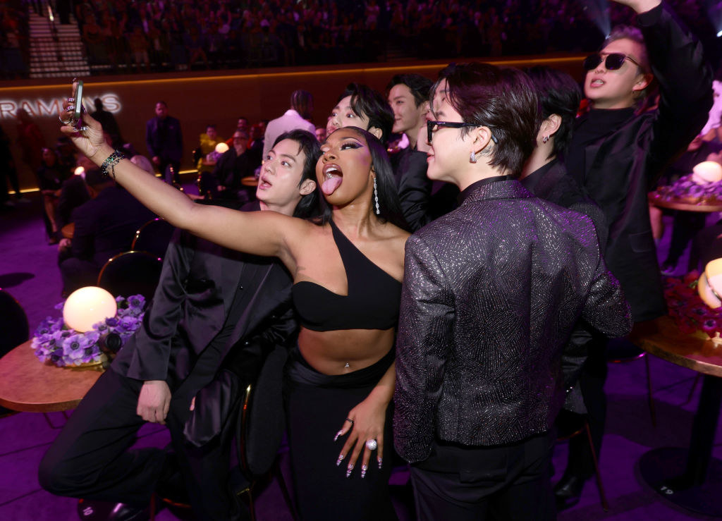 Megan takes a selfie while posing with members of BTS