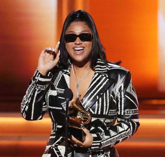 Jazmine wears sunglasses and holds an award