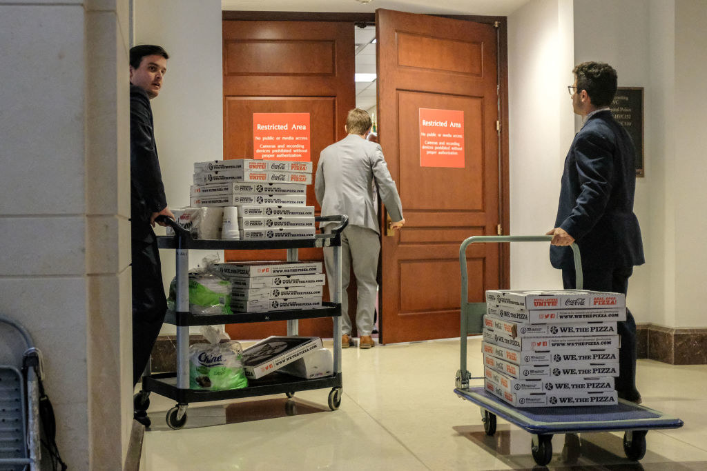 two carts filled with pizza boxes being rolled into a briefing room