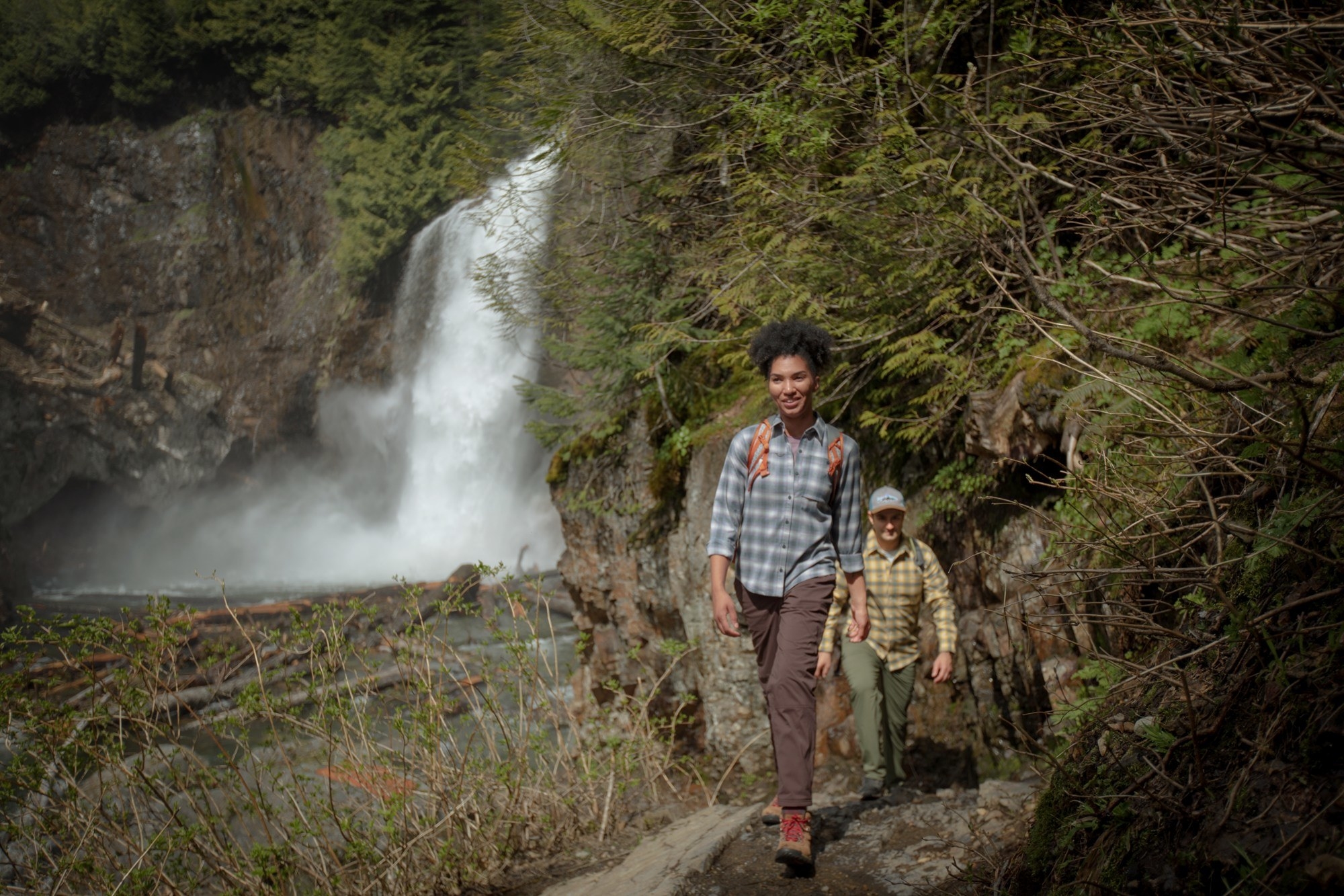 Two models wearing the thermal shirts while hiking along a waterfall