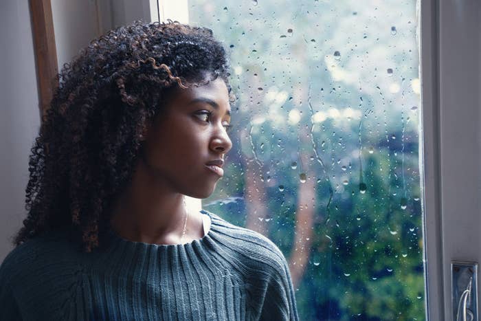 A woman staring out the window on a rainy day.