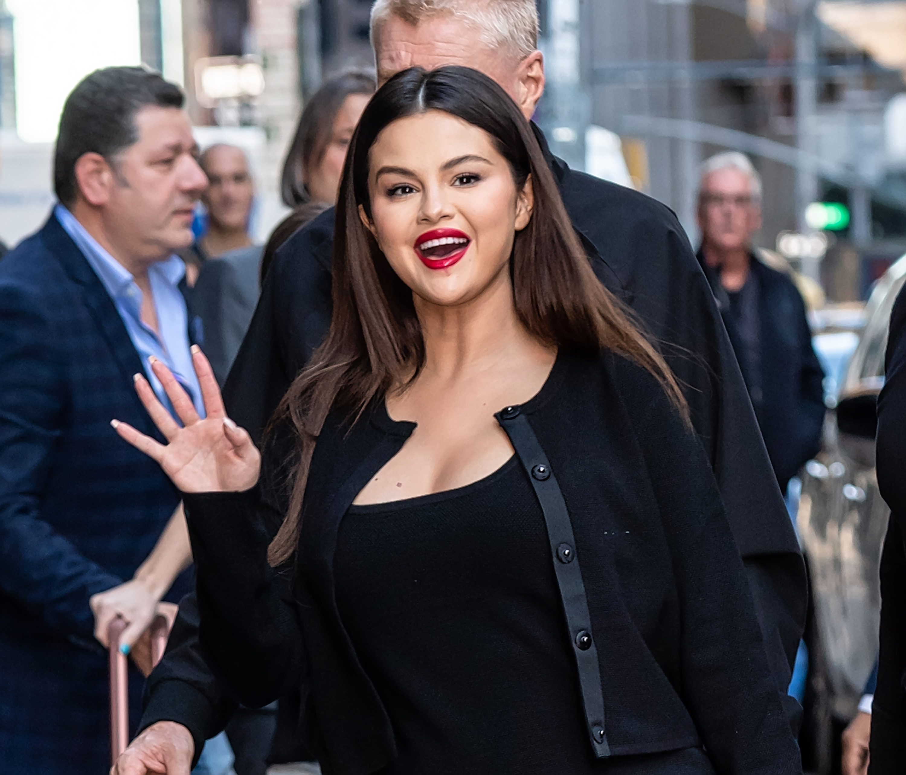 Selena waves her hand at a crowd while smiling