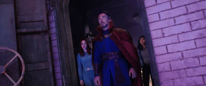 Doctor Strange stands in an open doorway in front of two women