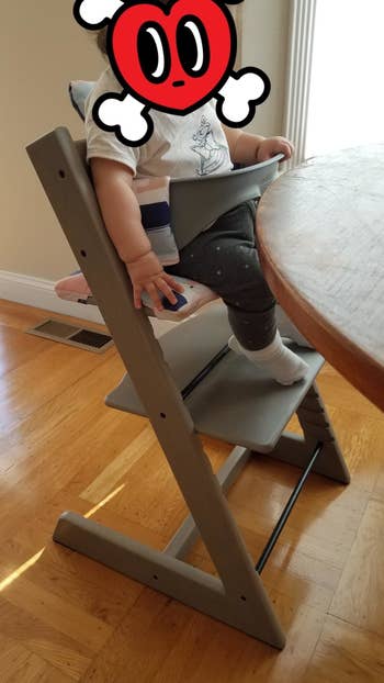 Reviewer's photo of their child sitting oak greywash color high chair