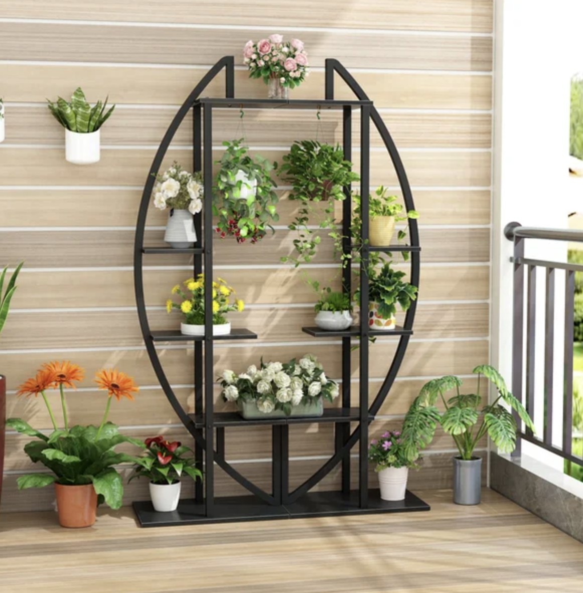 The black plant stand has multiple tiers, shelves and hooks