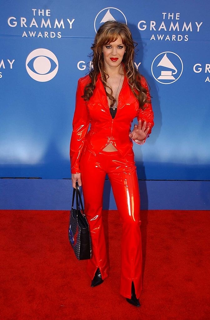 In a tight, shiny, colorful pantsuit and holding a handbag