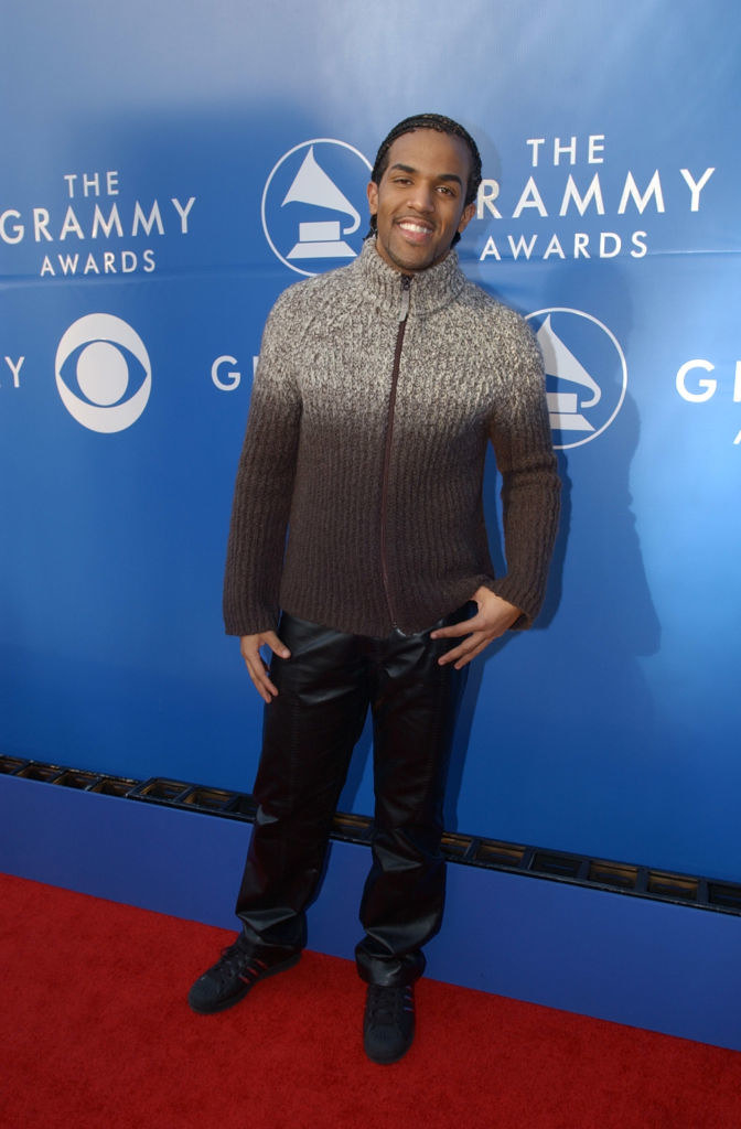 Wearing a zip-front turtleneck sweater and shiny, leather-looking pants