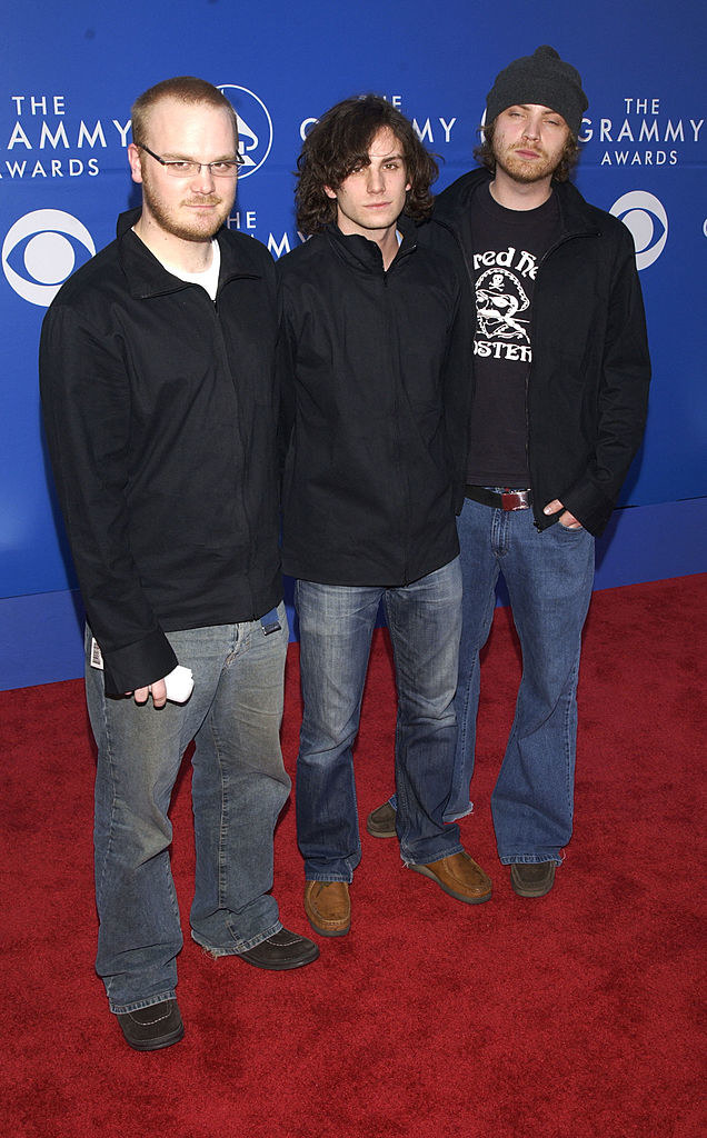Three guys wearing jeans and dark shirts