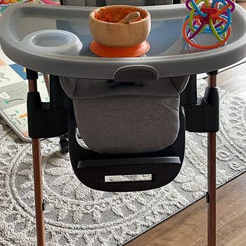 reviewer's photo of the high chair with a toy and a bowl of food on it