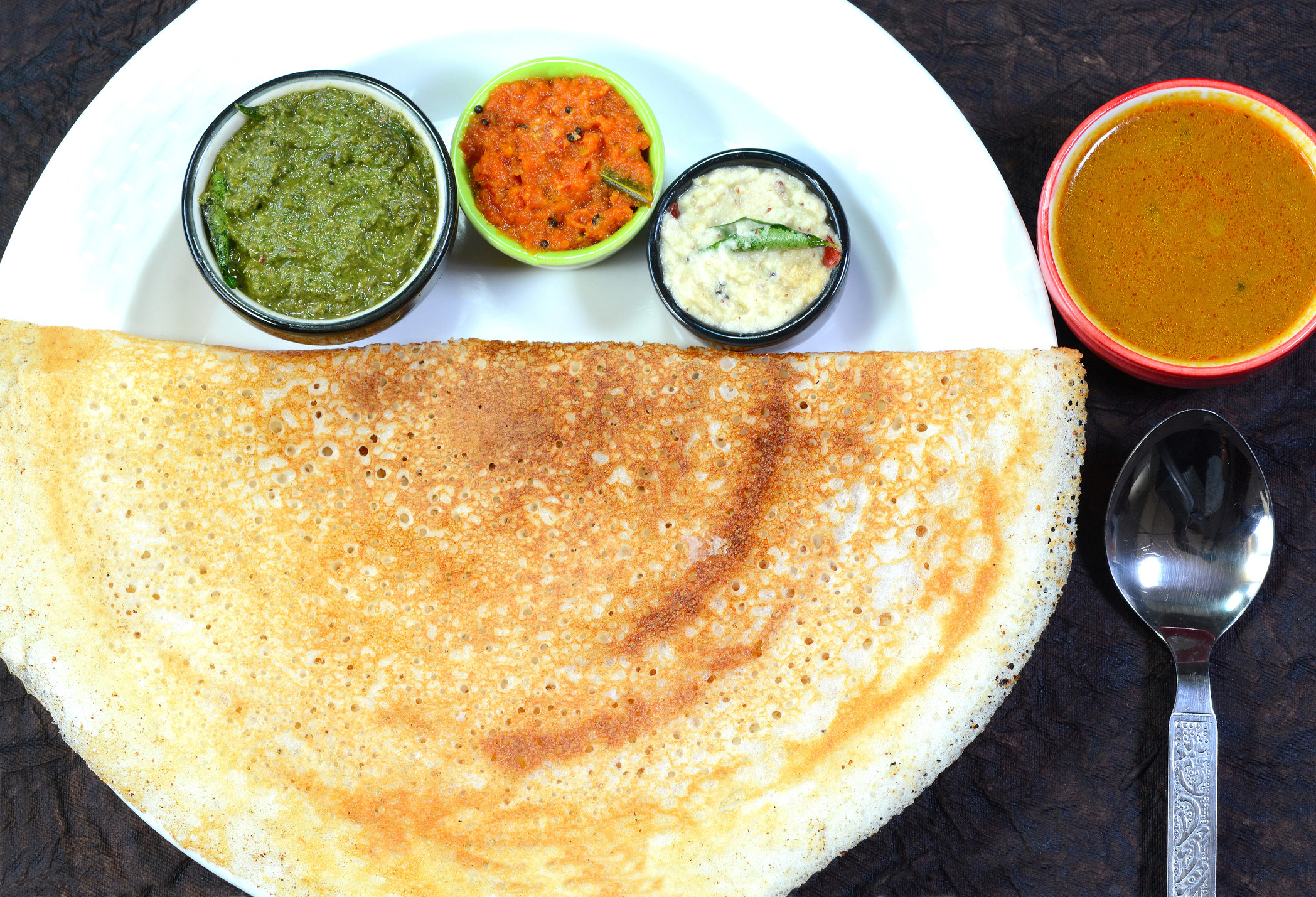A dosa, aka an Indian crepe, with four different condiments