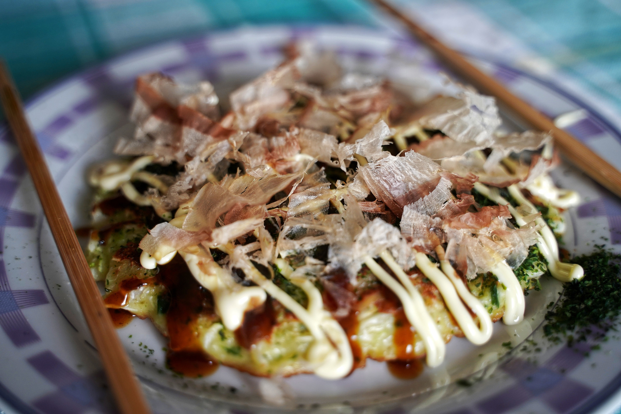 Okonomiyaki with lots of toppings and sauces on a plate