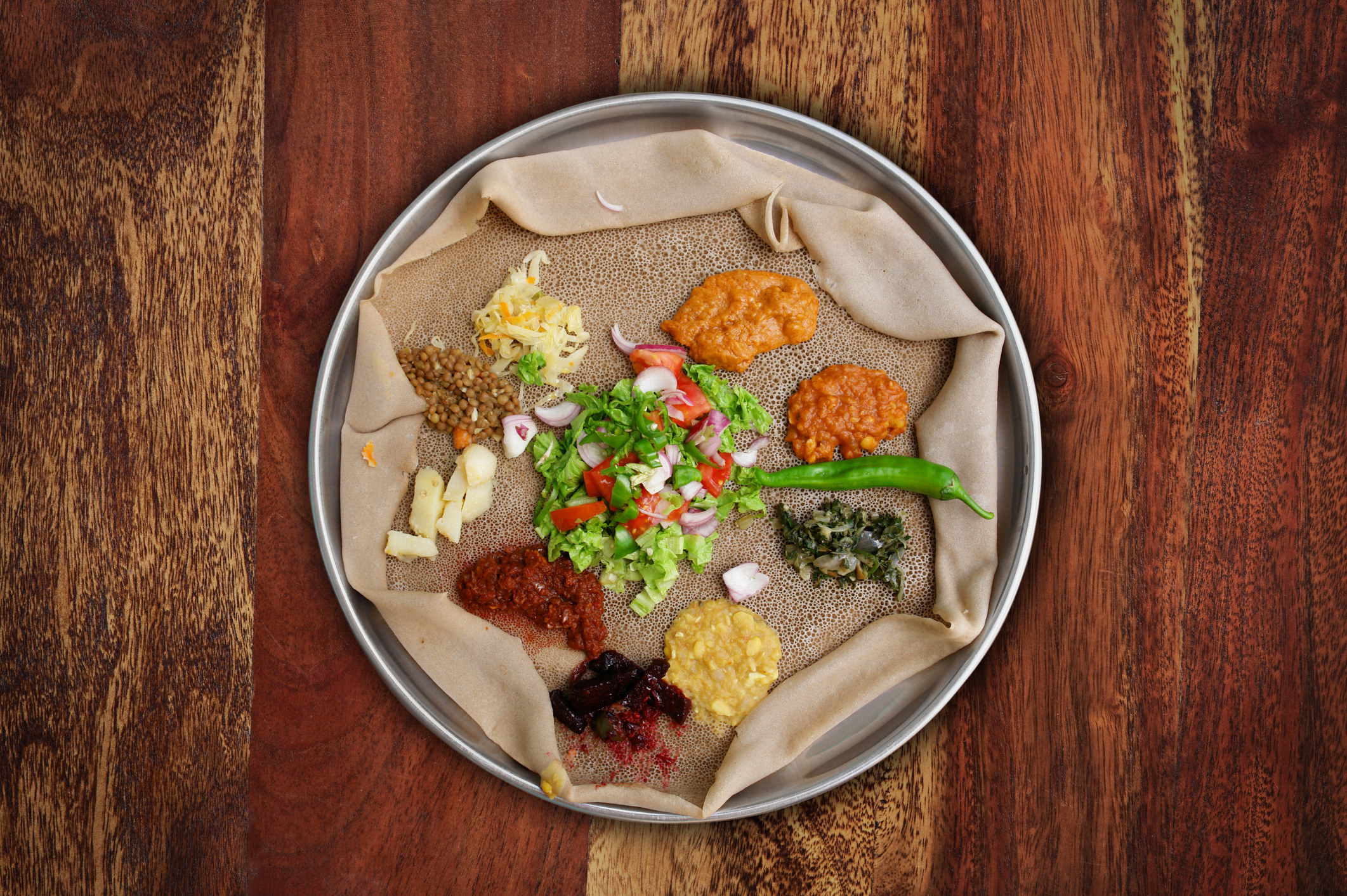 Injera, an Ethiopian flatbread, topped with different salads and condiments