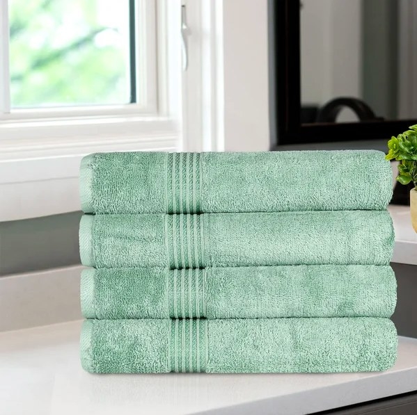 Four folded green towels stacked on top of each other