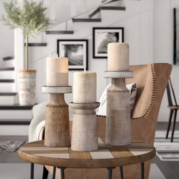 Three wooden candle holders with candles on an end table