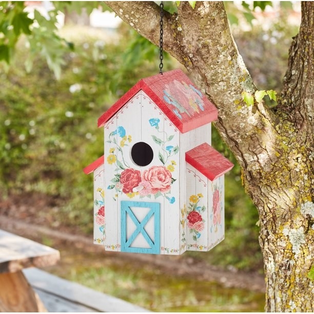 A colorful bird house hanging on a tree