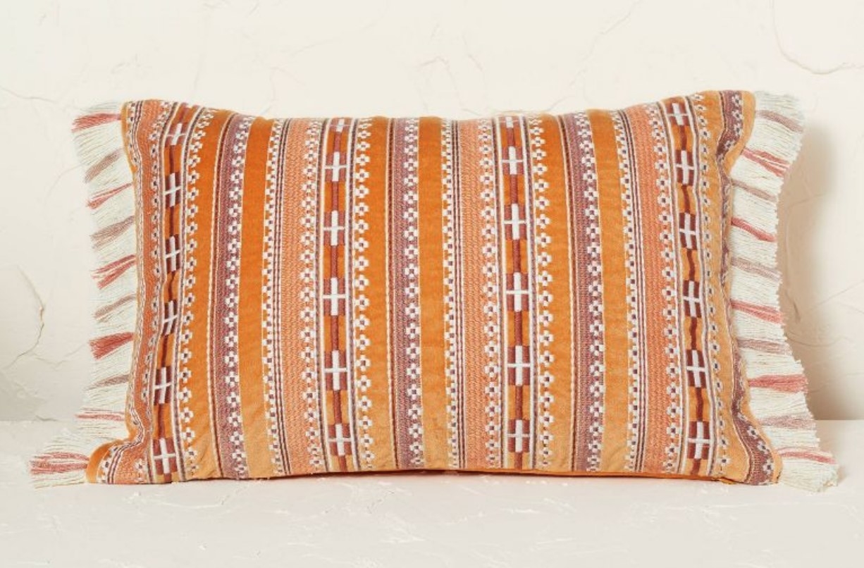 A velvet embroidered striped rust throw pillow