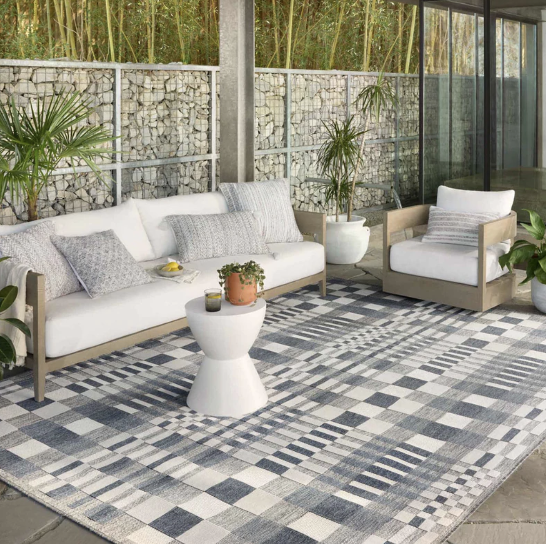 denim-print checkered gray and white rectangle rug under outdoor sofa and chair with white cushions