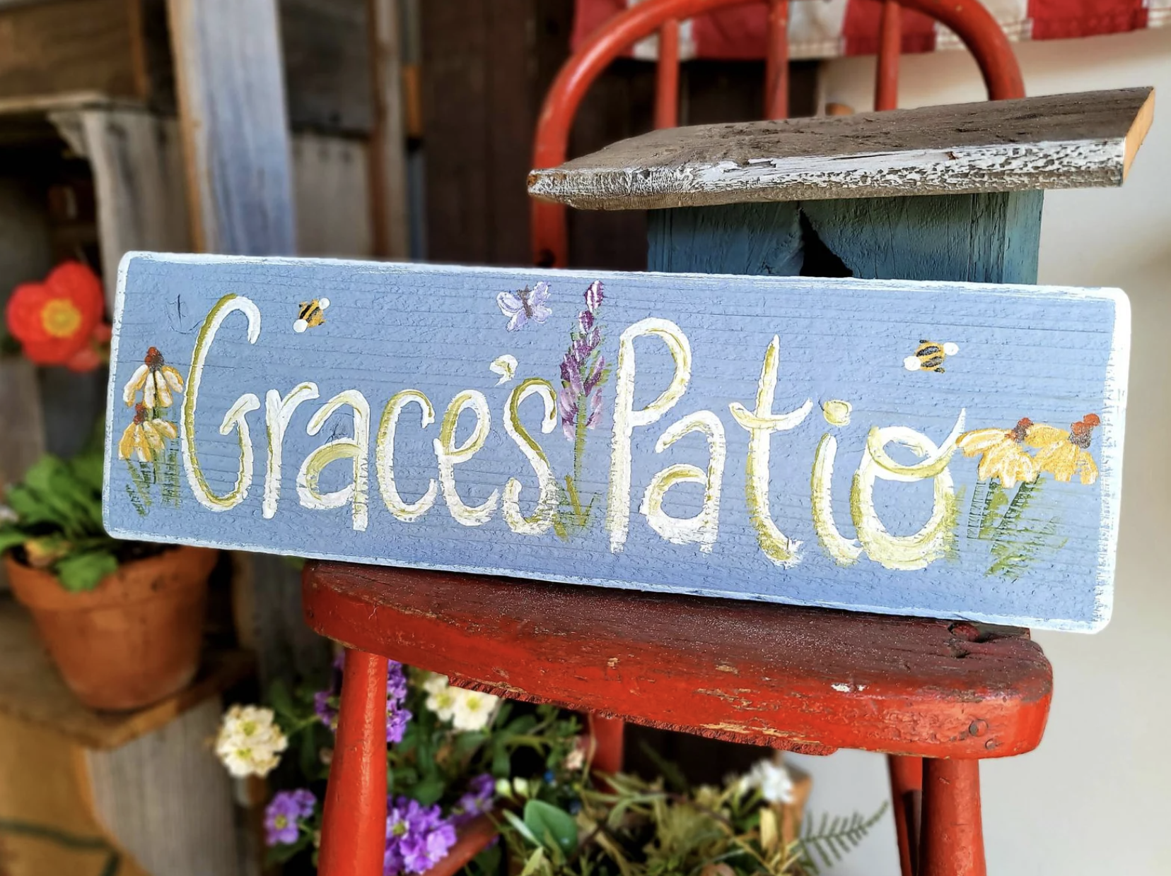 rectangle blue sign with hand-painted flowers that says &quot;Grace&#x27;s Patio&quot;