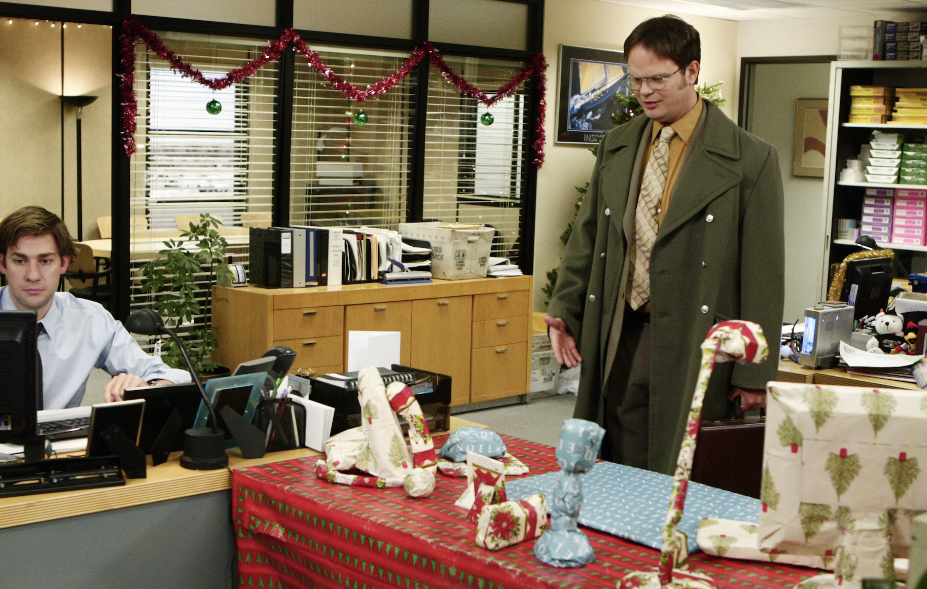 Rainn Wilson as Dwight Schrute looking at his desk that has been wrapped up like a present