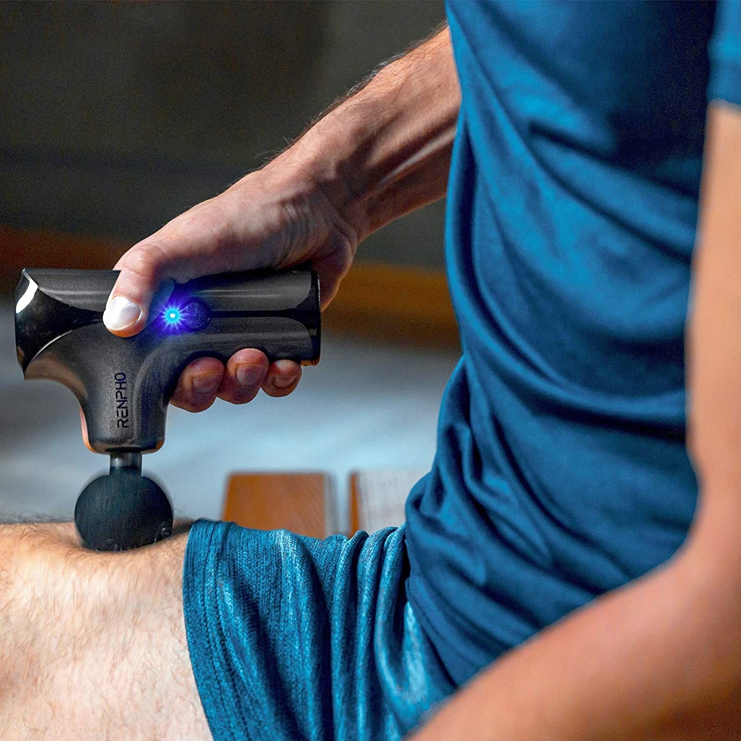 A person using the massage gun on their thigh