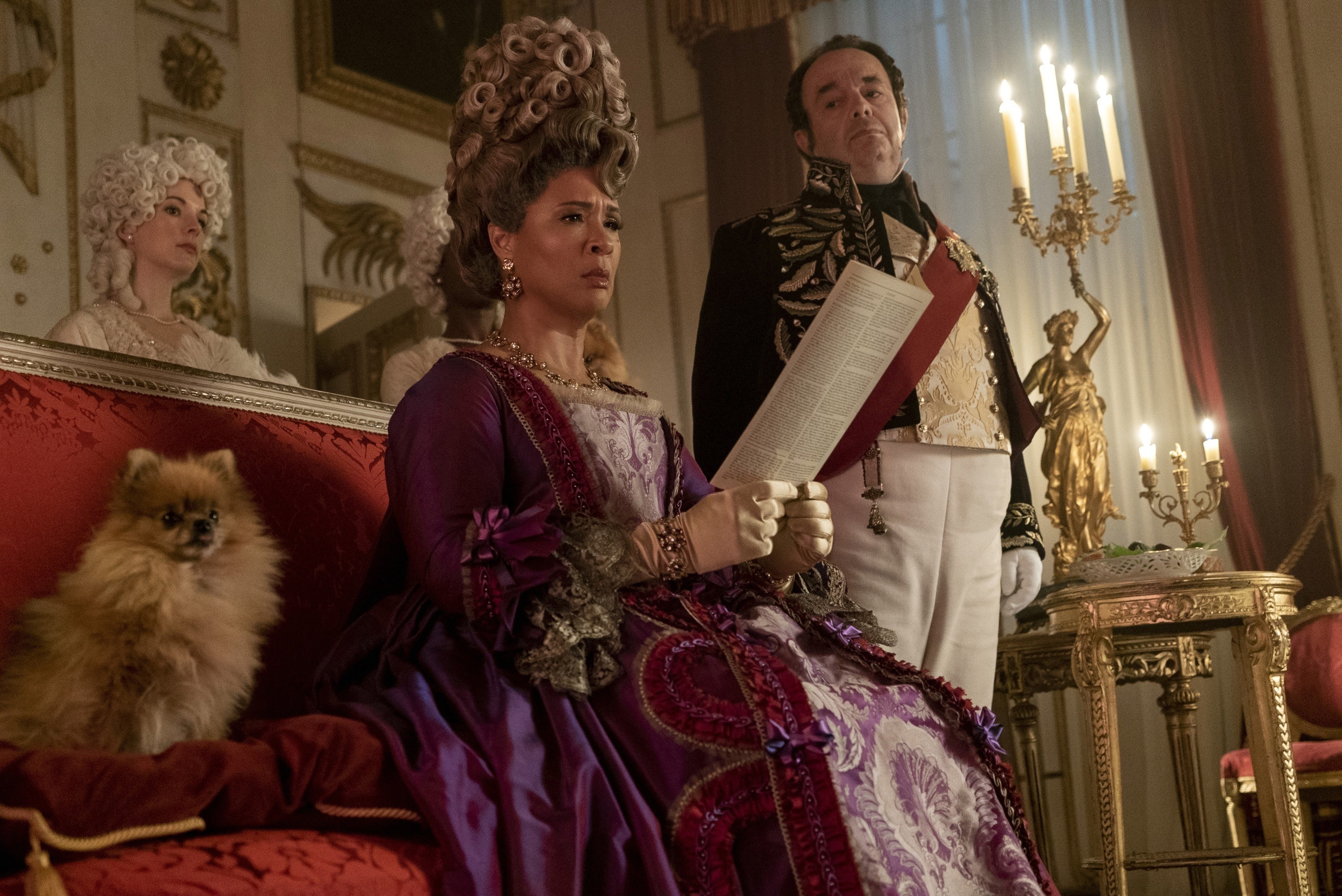 Golda Rosheuvel as Queen Charlotte looking at a paper while a man looks at her
