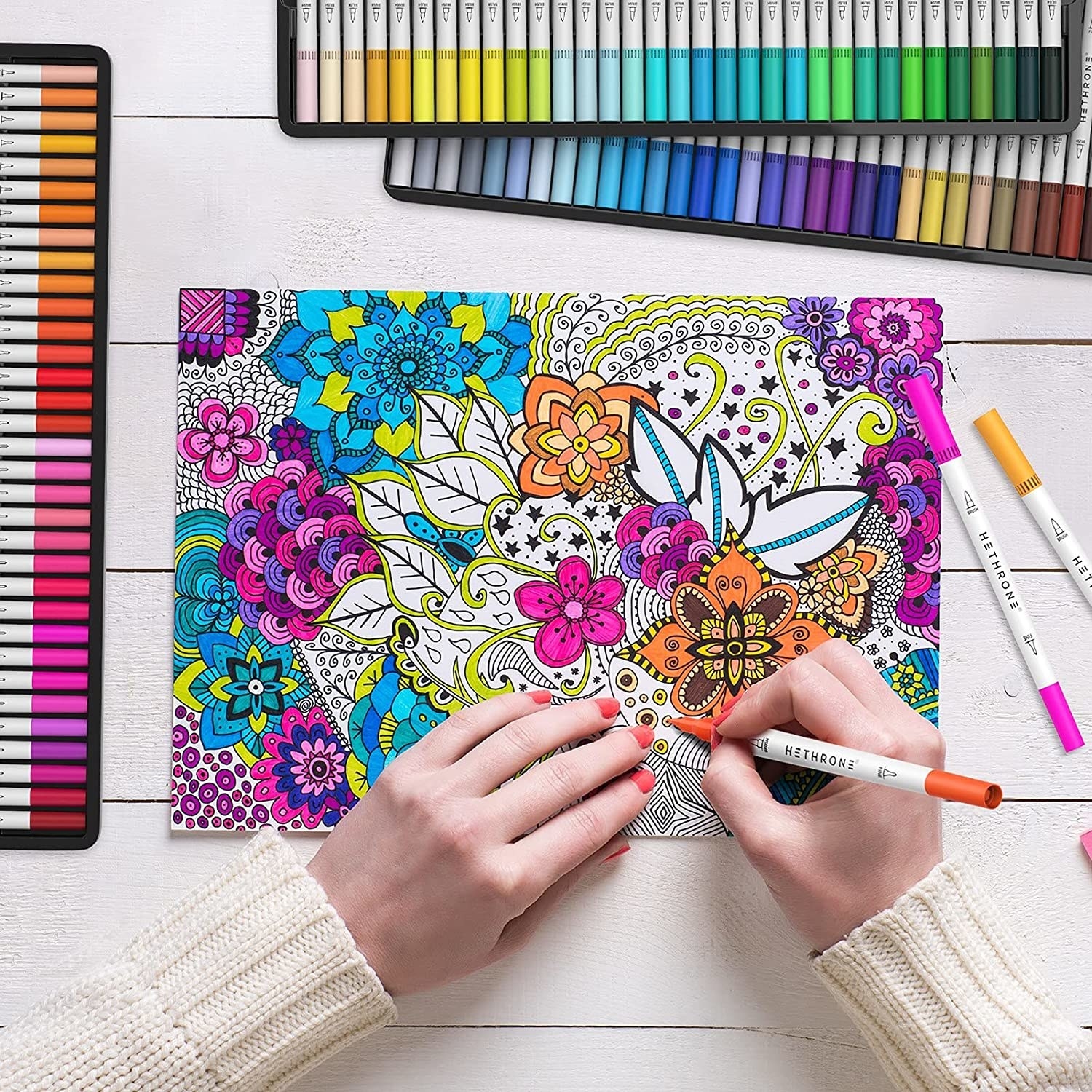 A person colouring a floral doodle with a marker