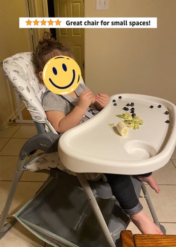 Reviewer's photo of their child eating in the high chair with the words 