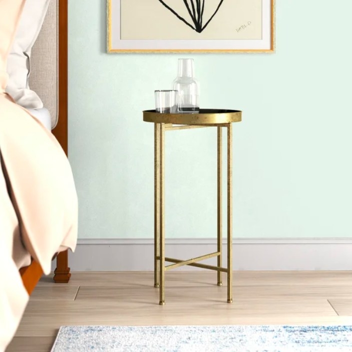 Gold end table next to a bed
