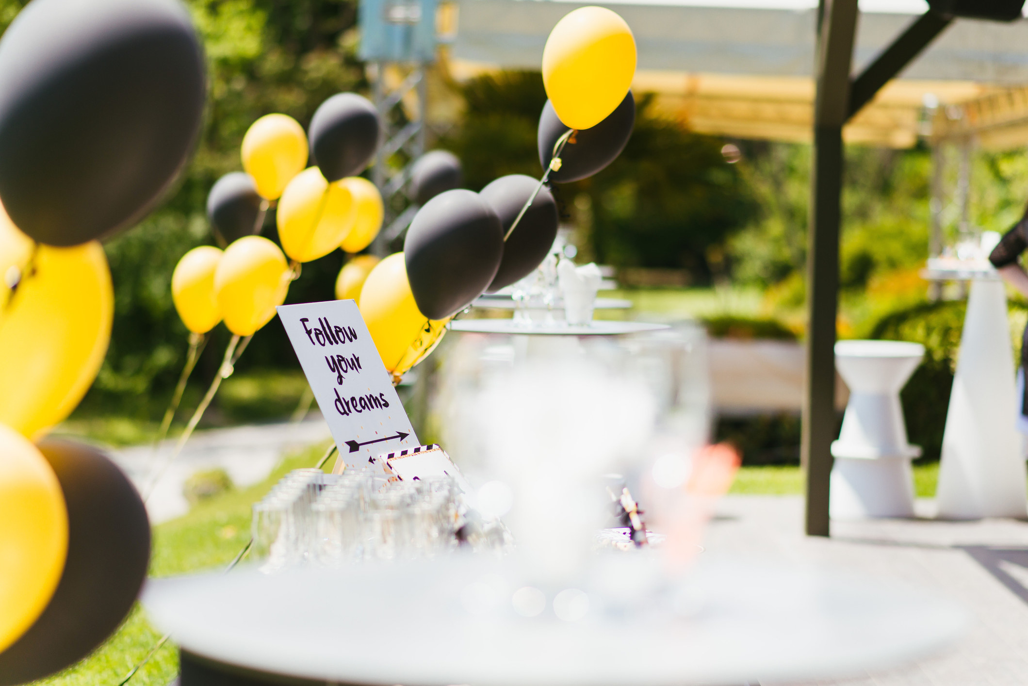 An outdoor party with different colored balloons and a sign that says &quot;follow your dreams&quot;