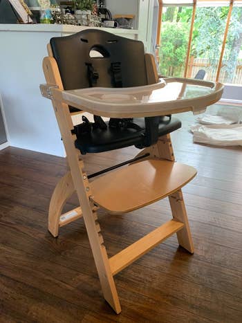 Reviewer's photo of the high chair with wooden legs and a black seat
