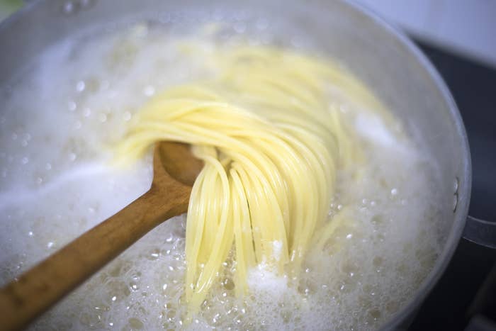 a wooden spoon in a pot of boiling pasta